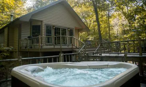 Un bain bouillonnant devant une cabane au milieu des arbres