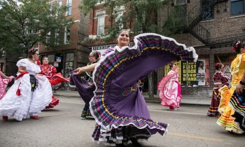 Des danseuses folkloriques virevoltent dans leurs costumes traditionnels lors d'un défilé de rue à Chicago.