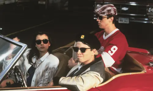 Image fixe tirée du film Ferris Bueller's Day Off, avec les trois acteurs principaux assis dans une Ferrari rouge décapotable