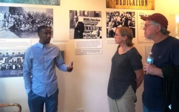 Un guide parle aux visiteurs d'une exposition devant laquelle ils se trouvent.