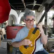 Ian Schneller gratte une guitare qu'il a fabriquée.