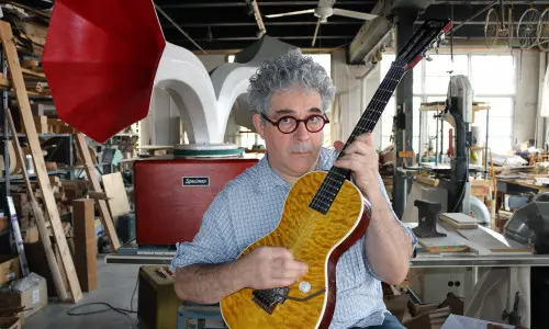 Ian Schneller gratte une guitare qu'il a fabriquée.