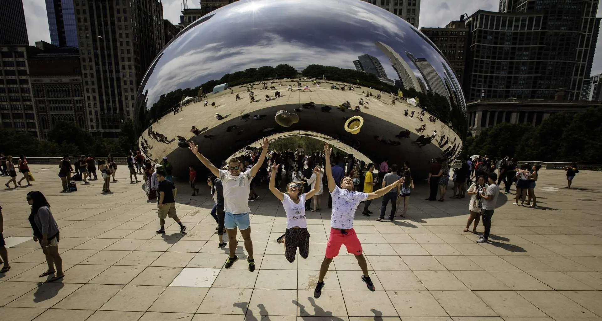 Trois personnes sautent en l'air devant le monument The Bean à Chicago.