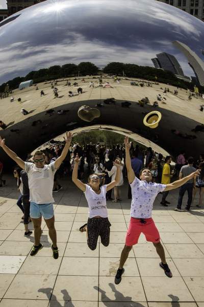 Trois personnes sautent en l'air devant le monument The Bean à Chicago.