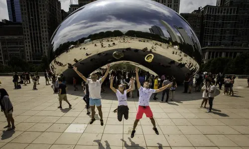 Trois personnes sautent en l'air devant le monument The Bean à Chicago.
