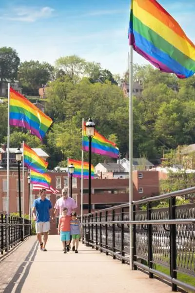 Des gens marchent le long d'un pont à Galena qui est bordé de drapeaux lgbt.