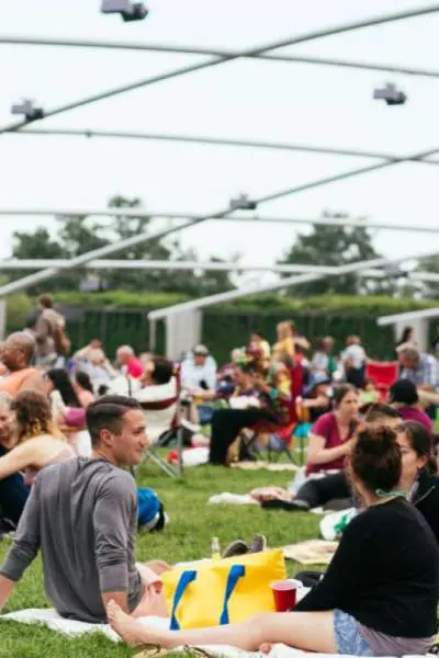 Un public nombreux assis sur l'herbe à l'extérieur du pavillon Pritzker