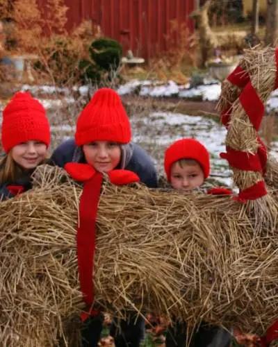 Trois enfants se cachent derrière une sculpture de foin festive