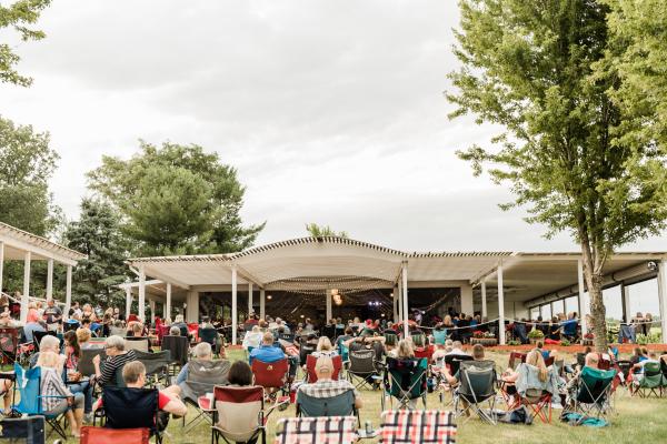 Personnes sur des chaises de jardin devant la scène musicale