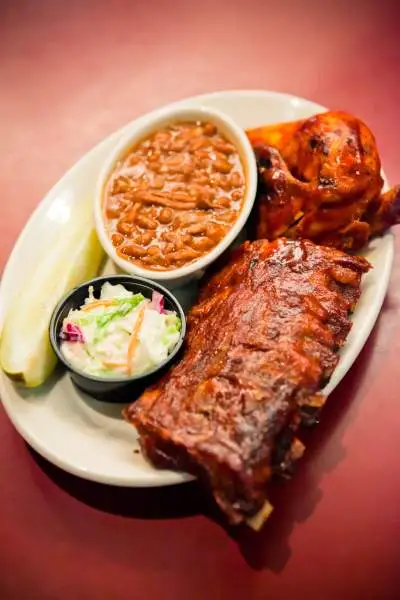 Une assiette de plats bbq comprenant des côtes, de la salade et des haricots.