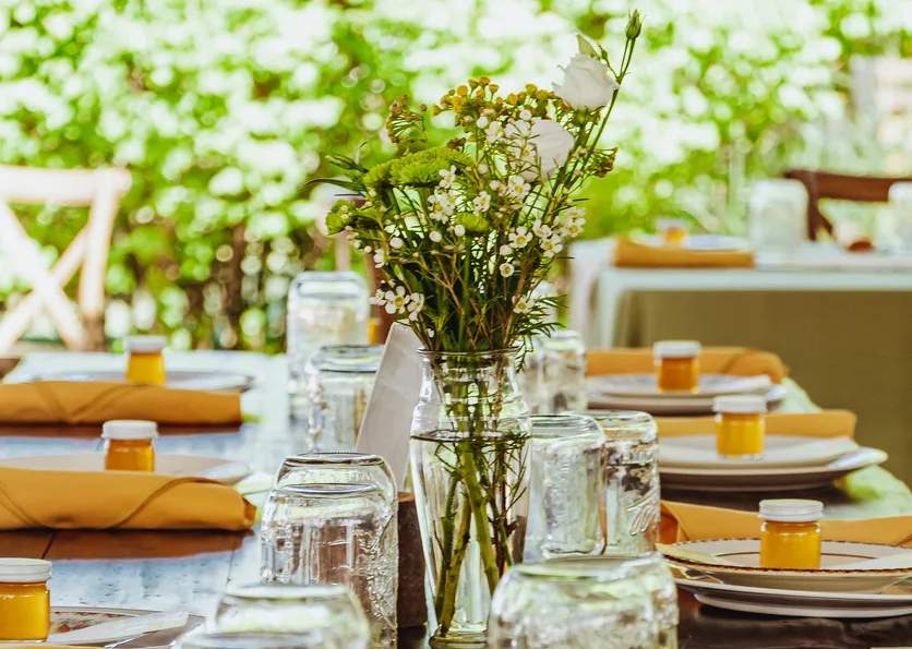 Une photo d'assiettes alignées le long d'une table de dîner avec des fleurs au milieu.