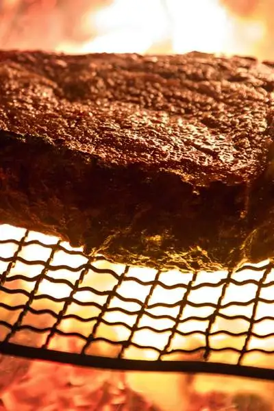 Un grand steak cuit sur une grille à la flamme nue