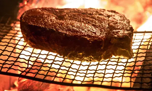 Un grand steak cuit sur une grille à la flamme nue