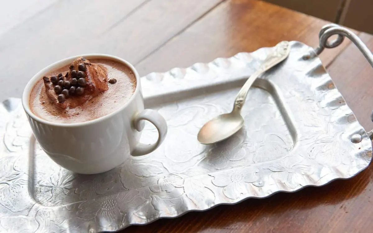 Une tasse de chocolat chaud et une cuillère à café posées sur un plateau de service