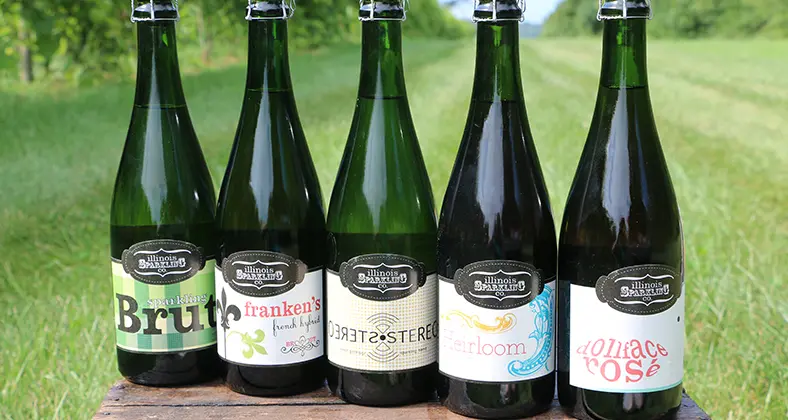 Cinq bouteilles de vin mousseux sur une caisse en bois