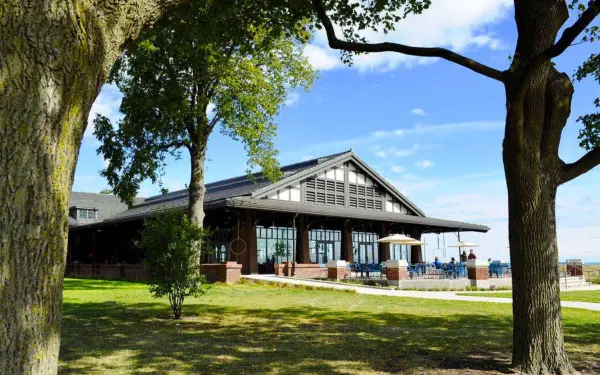 L'extérieur d'un restaurant au bord d'un lac avec des arbres au premier plan 