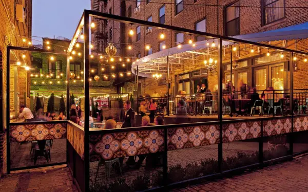 Les clients dînent dans le patio extérieur sous les lumières des ampoules.