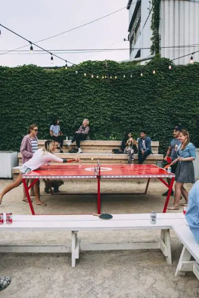 Les clients boivent des bières et jouent au tennis de table en plein air.