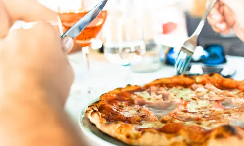 Personne mangeant une pizza avec un couteau et une fourchette