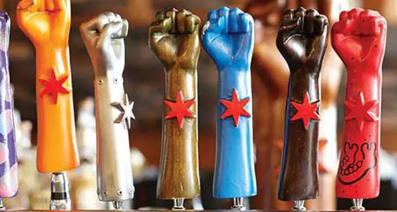 Un alignement de sept poignées de robinets de bière Revolution Brewing en forme de poings