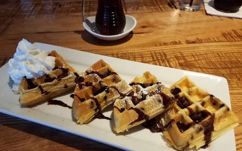 Gaufres alignées sur une assiette avec de la crème fouettée et du sirop