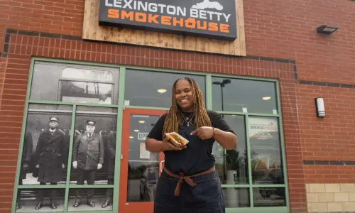 Une femme tenant un hot-dog devant le Lexington Betty Smokehouse.