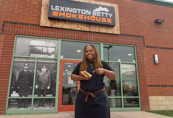 Une femme tenant un hot-dog devant le Lexington Betty Smokehouse.