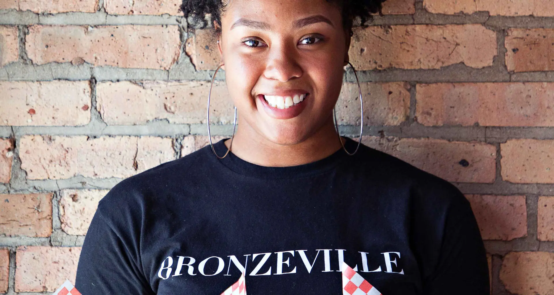 Femme tenant de la nourriture devant un mur de briques