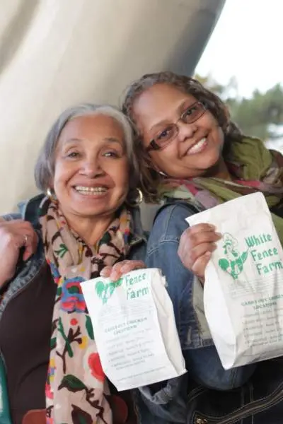 Deux femmes tenant des sacs de poulet frit de White Fence Farm
