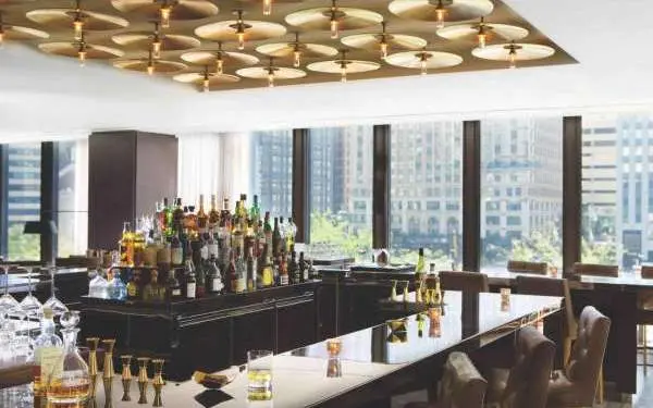 Intérieur d'un bar avec de nombreuses fenêtres donnant sur la ville.