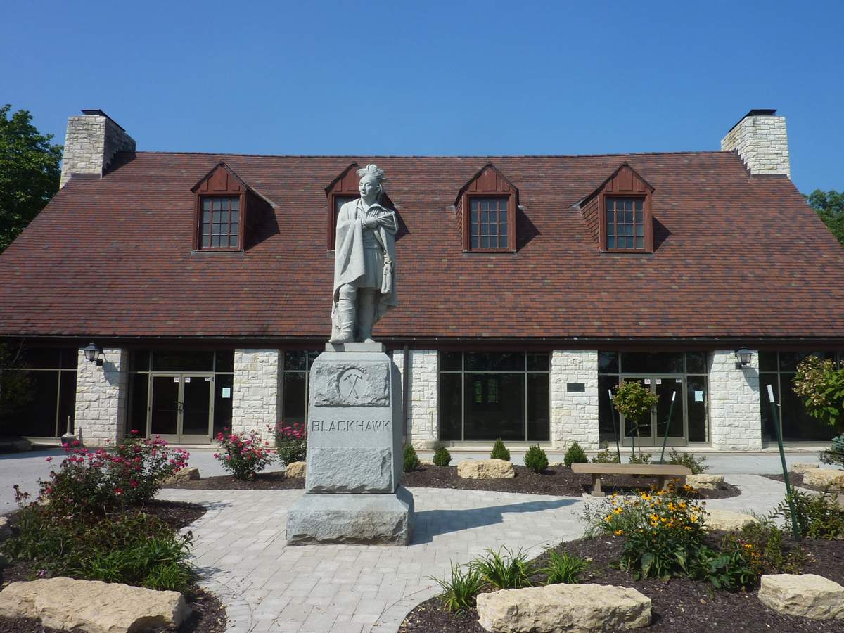 Une statue de Blackhawk devant un bâtiment à deux étages de faible hauteur.