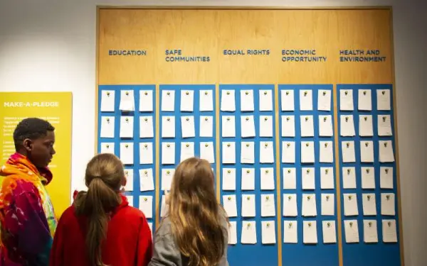 Des enfants regardent le tableau des promesses de dons recouvert de tuiles au musée de l'Holocauste.