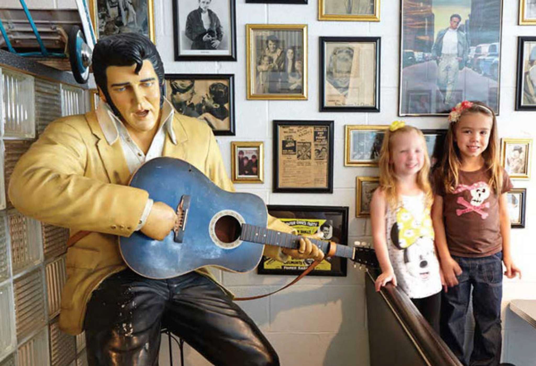 Deux jeunes se font photographier à côté d'une statue d'Elvis Presley tenant une guitare. 