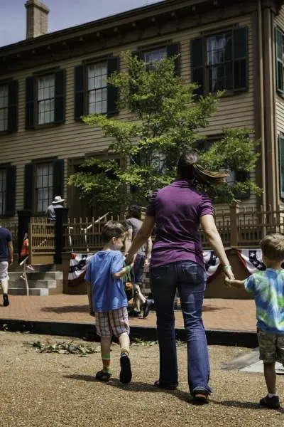 Une mère et ses enfants marchant vers la maison de Lincoln sur le site historique de la maison de Lincoln à Springfield.