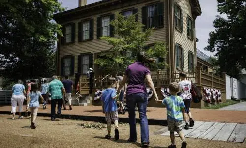 Une mère et ses enfants marchant vers la maison de Lincoln sur le site historique de la maison de Lincoln à Springfield.