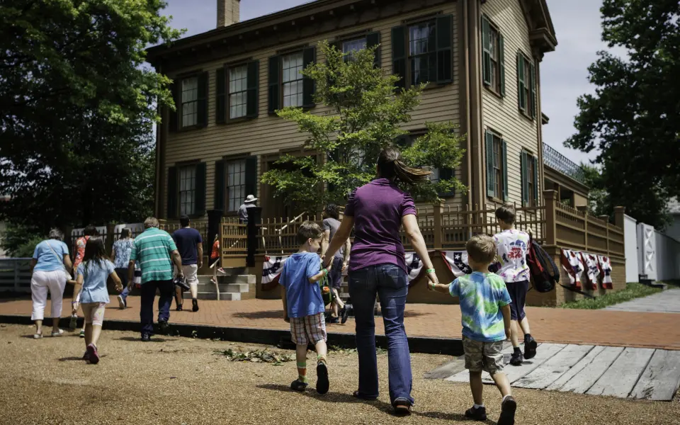 Une mère et ses enfants marchant vers la maison de Lincoln sur le site historique de la maison de Lincoln à Springfield.