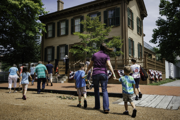 Une mère et ses enfants marchant vers la maison de Lincoln sur le site historique de la maison de Lincoln à Springfield.
