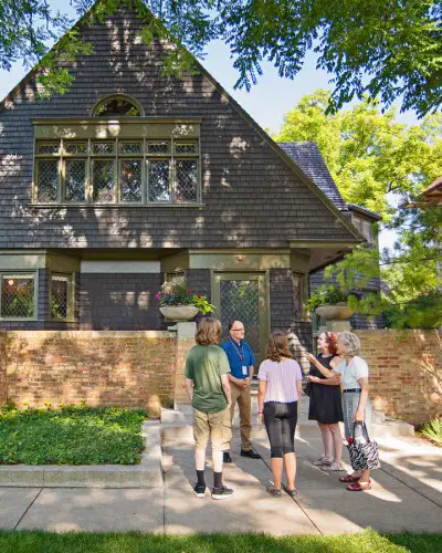 Un guide s'adresse à un groupe de visiteurs sur le trottoir devant la maison et l'atelier de Frank Lloyd Wright à Oak Park.