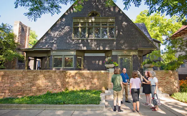 Un guide s'adresse à un groupe de visiteurs sur le trottoir devant la maison et l'atelier de Frank Lloyd Wright à Oak Park.