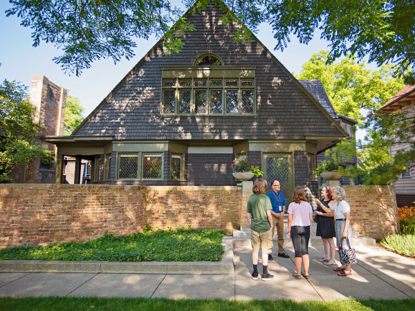 Un guide s'adresse à un groupe de visiteurs sur le trottoir devant la maison et l'atelier de Frank Lloyd Wright à Oak Park.