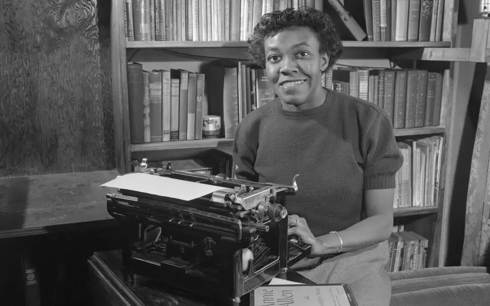 Femme assise à la machine à écrire dans une bibliothèque