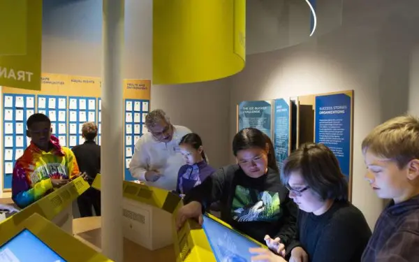 Enfants et adultes utilisant les écrans interactifs du musée de l'Holocauste