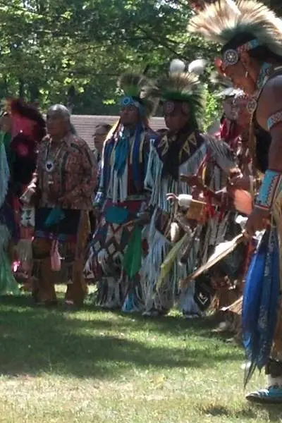 Un groupe d'hommes en tenue amérindienne dans une clairière au milieu des arbres