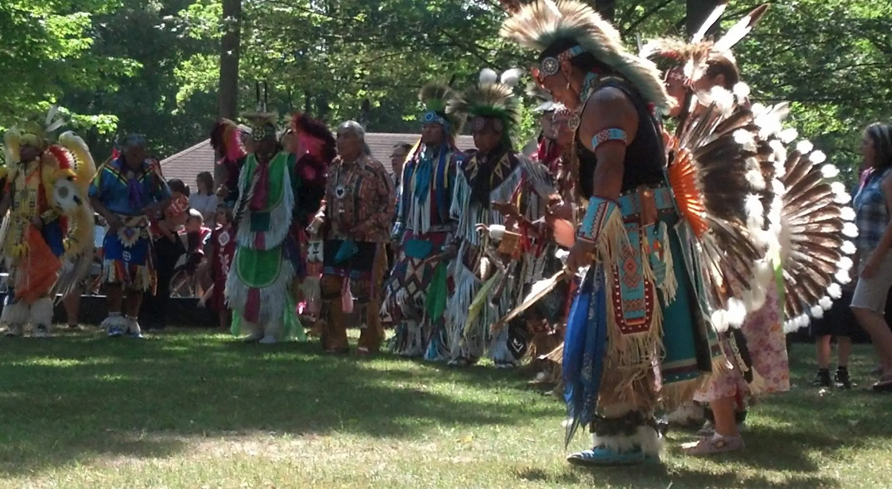 Un groupe d'hommes en tenue amérindienne dans une clairière au milieu des arbres