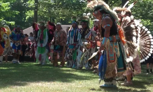 Un groupe d'hommes en tenue amérindienne dans une clairière au milieu des arbres