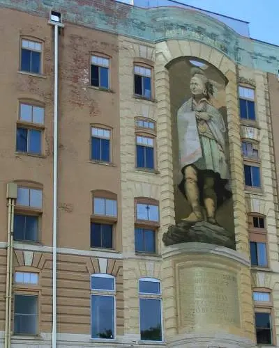 Une grande peinture murale de Blackhawk, haute de trois étages, sur la façade d'un bâtiment en briques.