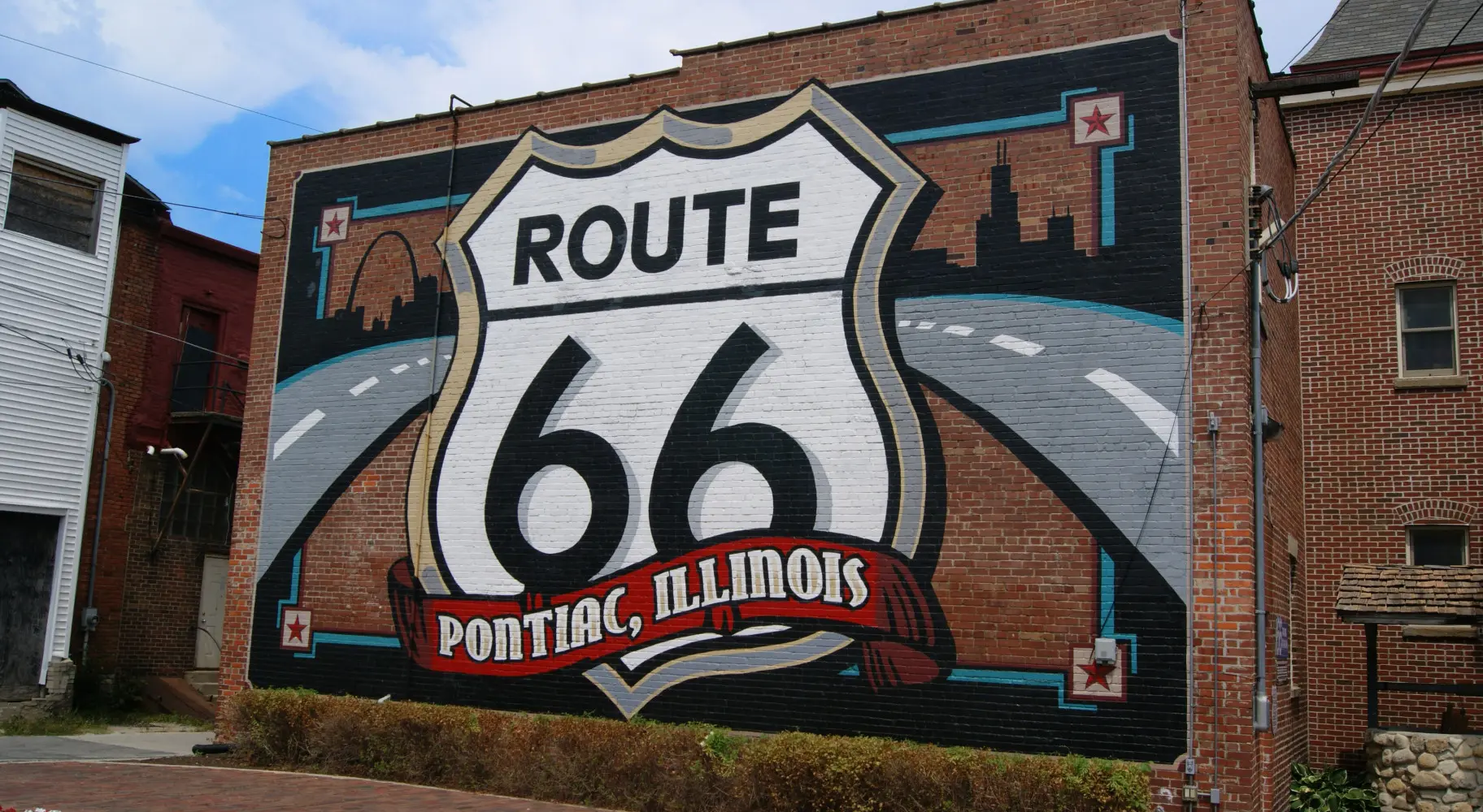 Un mur de briques avec une grande peinture murale de la Route 66