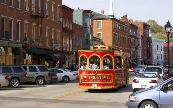 Un trolleybus rouge descend la rue principale de Galena, entouré de voitures garées et de bâtiments en briques.
