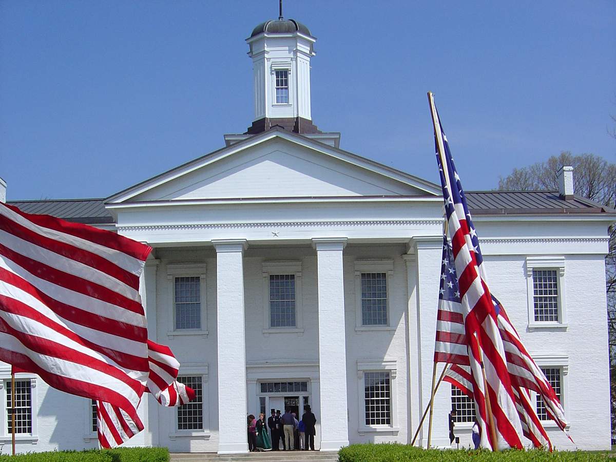 Une grande maison blanche avec des drapeaux américains à l'avant