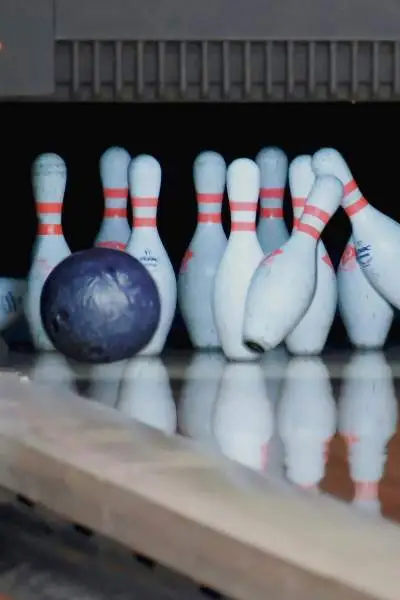 Des boules de bowling s'écrasent sur des quilles dans un bowling